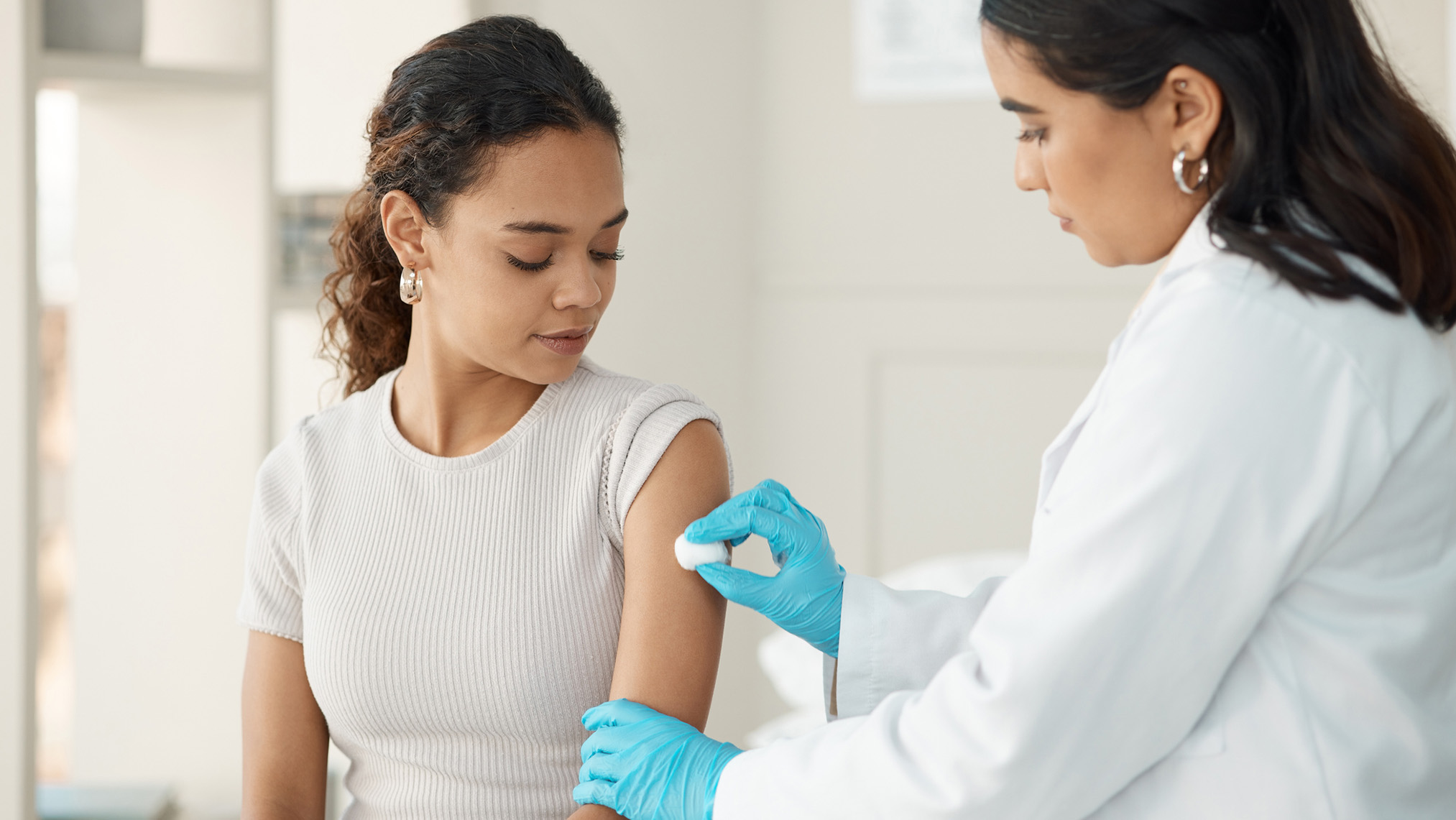 A girl seated with a doctor preparing to administer a vaccine.